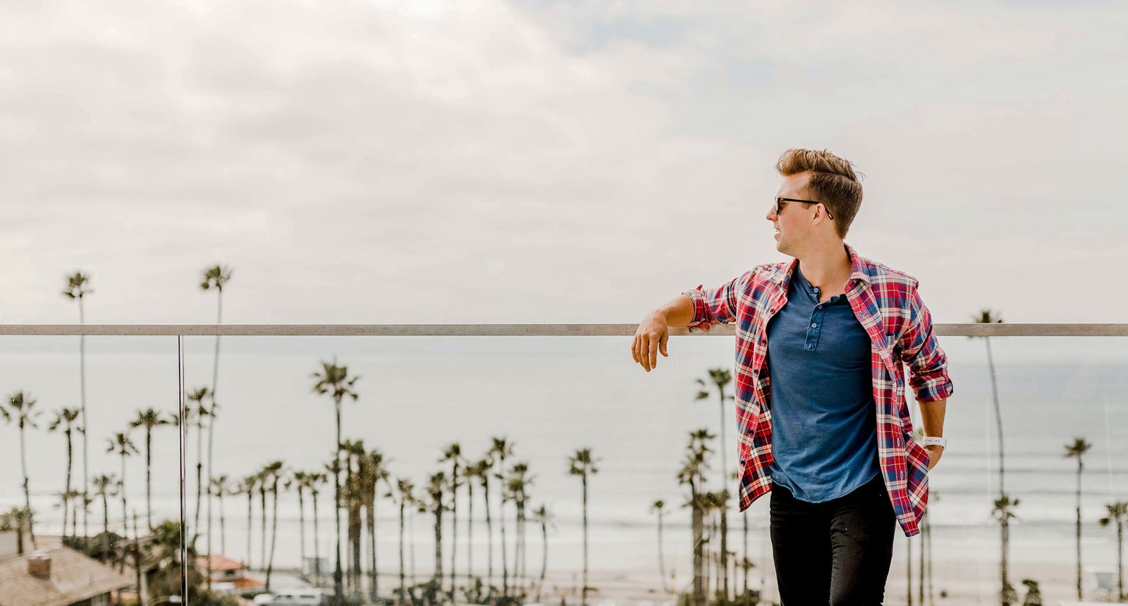 Man walking past palm trees on a sunny day